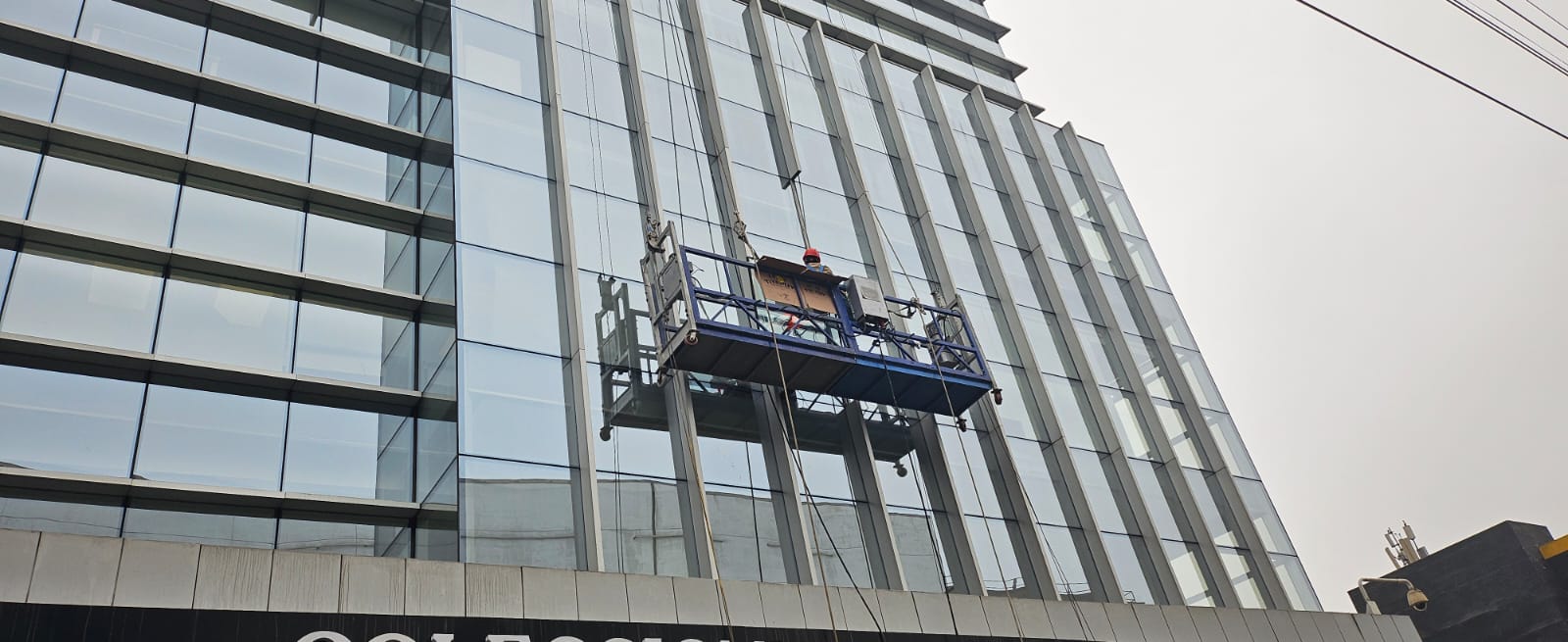 Plataforma suspendida trabajando sobre una fachada acristalada